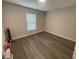 Empty room with wood-style flooring and a window, presenting a versatile space for customization and personalization at 3338 Sw 165Th Loop, Ocala, FL 34473