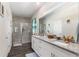 Bright bathroom featuring double sink vanity with granite counters, tiled shower, and wood-look tile floors at 4064 Sw 132Nd Ln, Ocala, FL 34473