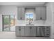 Bright kitchen with gray cabinets, stainless appliances, and an undermount sink with sliding doors at 4312 Sw 172Nd Place Rd, Ocala, FL 34473