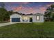 Charming single-story home featuring a well-manicured lawn and a two-car garage at dusk at 46 Fisher Lane Ter, Ocklawaha, FL 32179