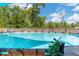 Clear blue swimming pool surrounded by a wooden fence and green trees at 46 Fisher Lane Ter, Ocklawaha, FL 32179