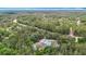 Aerial view showcases a charming green home surrounded by lush trees near a winding road and waterway at 505 Fisher Rd, Ocklawaha, FL 32179