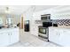 Bright kitchen featuring stainless range and microwave, tiled backsplash and white cabinetry at 505 Fisher Rd, Ocklawaha, FL 32179