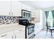 Bright kitchen featuring stainless range and microwave, tiled backsplash and white cabinetry at 505 Fisher Rd, Ocklawaha, FL 32179