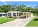 Light yellow single-story home featuring a large carport, lovely lawn, and landscaping at 518 Saint Andrews Blvd, Lady Lake, FL 32159