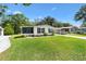 Quaint single-story home with lush lawn, carport, and screened porch in a serene setting at 518 Saint Andrews Blvd, Lady Lake, FL 32159
