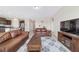 Comfortable living room with neutral colors, tile floors, and leather couches adjacent to a kitchen area at 5653 Sw 50Th Ter, Ocala, FL 34474