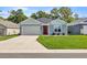 Charming single-story home with a well-manicured lawn, inviting red door, and attached garage at 6557 Se 4Th Ln, Ocala, FL 34472