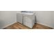 A laundry room with modern washer and dryer units on a wood floor at 7199 Sw 60Th Ln, Ocala, FL 34474