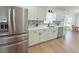Modern kitchen features stainless steel refrigerator, white cabinets, and open layout to dining area at 9029 Se 135Th Loop, Summerfield, FL 34491