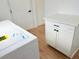 Bright laundry room featuring a new white washing machine, cabinets and wood-look floors at 9029 Se 135Th Loop, Summerfield, FL 34491