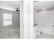 Hallway view showing a bedroom with a ceiling fan adjacent to a bright, tiled bathroom with a tub and vanity at 9266 Sw 58Th Cir, Ocala, FL 34476