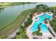 A beautiful swimming pool complex with palm trees, lounge chairs, lake and golf course in this aerial view of the community at 9459 Sw 52Nd Loop, Ocala, FL 34481