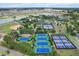 Aerial view of a community with multiple tennis courts, a baseball field, parking, lake, and many single Gathering homes at 9459 Sw 52Nd Loop, Ocala, FL 34481