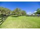 Expansive green lawn with mature trees and black fencing on a sunny day at 9462 Sw 72Nd Ct, Ocala, FL 34476