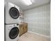 Convenient laundry room with modern washer and dryer, custom wallpaper, and storage cabinets at 9462 Sw 72Nd Ct, Ocala, FL 34476