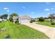 Well-manicured front lawn of single story home with a spacious driveway and attached two car garage at 9853 Se 175Th Pl, Summerfield, FL 34491