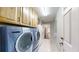 A well-lit laundry room with cabinets, tile floors, and included washer and dryer units at 10528 Sw 27Th Ave, Ocala, FL 34476