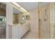 Bathroom featuring large vanity with mirror, glass enclosed shower and neutral striped wallpaper at 11586 Sw 75Th Cir, Ocala, FL 34476
