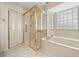 Bathroom with a glass-enclosed shower and a separate tub beneath a window with privacy blinds at 11586 Sw 75Th Cir, Ocala, FL 34476