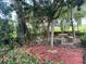 Outdoor dining area featuring a stone picnic table, mature trees, and deck at 1408 Torrey Pines Dr, Lady Lake, FL 32159