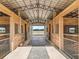 Interior view of horse barn featuring individual stalls with metal gates and a view of distant fields at 5330 Ne 111Th Lane Rd, Anthony, FL 32617