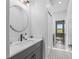 Well-lit bathroom with modern vanity, round mirror, patterned tile, and hallway leading to pasture view at 5330 Ne 111Th Lane Rd, Anthony, FL 32617