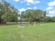 Sprawling backyard with tidy raised garden beds and large trees against a backdrop of blue sky at 5330 Ne 111Th Lane Rd, Anthony, FL 32617