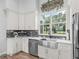 Bright kitchen features a stainless steel sink, white cabinetry, granite counters and a beautiful backyard view at 5330 Ne 111Th Lane Rd, Anthony, FL 32617