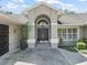 Elegant home entrance with a black double door, arched transom window, and decorative plants and gravel at 5714 Nw 80Th Avenue Rd, Ocala, FL 34482