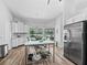 Well-lit kitchen featuring white cabinets, stainless appliances, an island, and a view of the outdoor pool area at 5714 Nw 80Th Avenue Rd, Ocala, FL 34482
