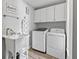 Well-lit laundry room with a sink, washer, dryer, and overhead storage cabinets at 5714 Nw 80Th Avenue Rd, Ocala, FL 34482
