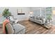 Stylish living room with wood-look tile floors, a comfortable grey sofa, and natural light from the windows at 5714 Nw 80Th Avenue Rd, Ocala, FL 34482