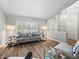 Bright living room features wood-look floors, comfortable furniture, and a view of the front yard at 5714 Nw 80Th Avenue Rd, Ocala, FL 34482