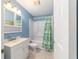 Bathroom features a shower-tub combo, modern vanity, and cactus shower curtain at 6060 Se 119Th Pl, Belleview, FL 34420