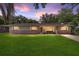 A beautifully lit one-story home with brick accents, a green lawn, and a colorful evening sky at 6060 Se 119Th Pl, Belleview, FL 34420