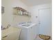 Small laundry room with wash basin, white washer and dryer, and exterior door at 6211 Se 126Th St, Belleview, FL 34420