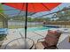 A red umbrella offers shade next to the glistening screened-in pool, perfect for hot summer days at 6211 Se 126Th St, Belleview, FL 34420
