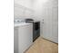 Tiled laundry room includes washer and dryer, metal shelving, and a white door at 7270 Sw 99Th Cir, Ocala, FL 34481