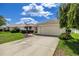 Single-story home with a well-manicured lawn and long driveway to an attached garage at 8352 Se 168Th Trinity Pl, The Villages, FL 32162