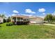 A sunny single-story home featuring lush green lawn, mature landscaping, and an attached garage at 8352 Se 168Th Trinity Pl, The Villages, FL 32162
