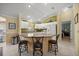Well-lit kitchen with white cabinets, breakfast bar, and views into an adjacent room at 8352 Se 168Th Trinity Pl, The Villages, FL 32162
