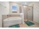 Bathroom featuring a tub, a window with blinds, a glass-enclosed shower, and green bath mats at 8870 Sw 62Nd Ave, Ocala, FL 34476