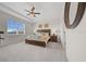 Bright main bedroom featuring a tray ceiling, a ceiling fan, carpet flooring, and a view of the front yard at 8870 Sw 62Nd Ave, Ocala, FL 34476