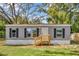 Single story home features low wood porch, gray siding, and black window shutters at 9100 Sw 32Nd Ct, Ocala, FL 34476