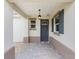 Charming covered front porch with stylish gray door, modern lighting, and neutral stone flooring at 10427 Sw 98Th Place Rd, Ocala, FL 34481