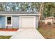 Attached garage with a white door, flanked by exterior lights, with a freshly sealed driveway at 13793 Sw 100 Ln, Dunnellon, FL 34432
