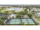 Aerial view showcases a community pool, tennis courts, golf course, lake and lush landscaping amidst a charming neighborhood at 2608 Casso Ct, The Villages, FL 32162