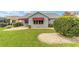 This home features a well-manicured lawn, beautiful bushes, rock ground cover, and red awnings over the windows at 2608 Casso Ct, The Villages, FL 32162