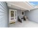 Inviting front porch with seating area, neutral siding, and decorative front door with sidelights at 2608 Casso Ct, The Villages, FL 32162
